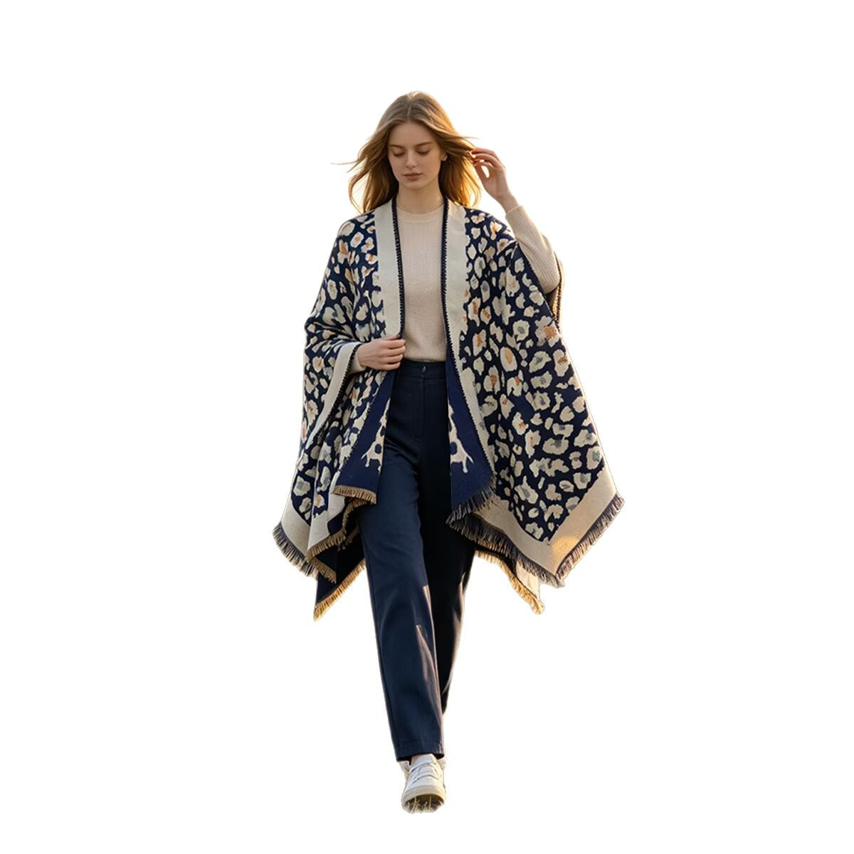 A woman modeling a navy blue and beige patterned shawl with fringe, worn open over a cream top and navy pants, against a solid white background.