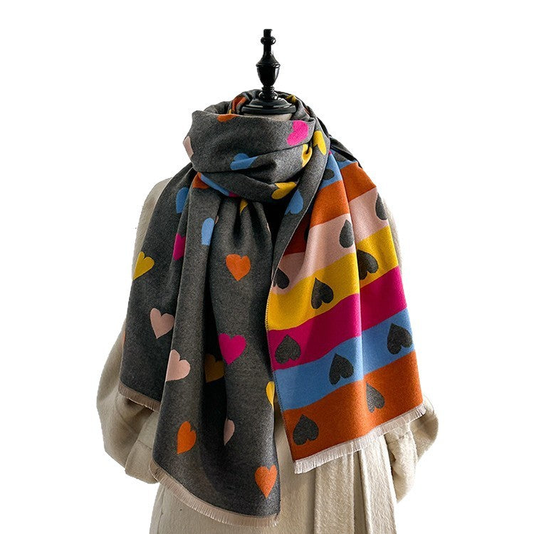 A multicolor knit scarf with heart motifs draped on a cream-colored dress form mannequin against a solid white background.