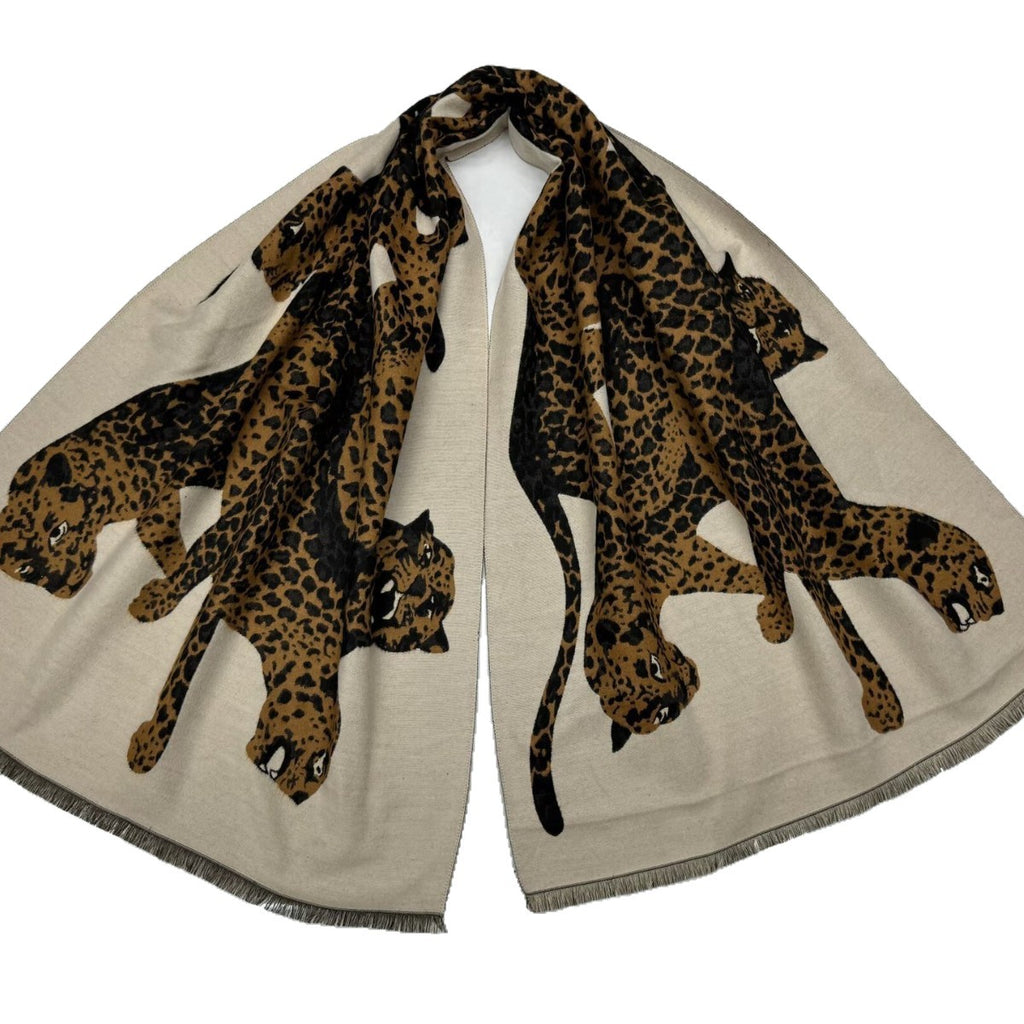 A beige scarf with a double print of leopards in black and brown, featuring fringed edges, displayed on a white background.