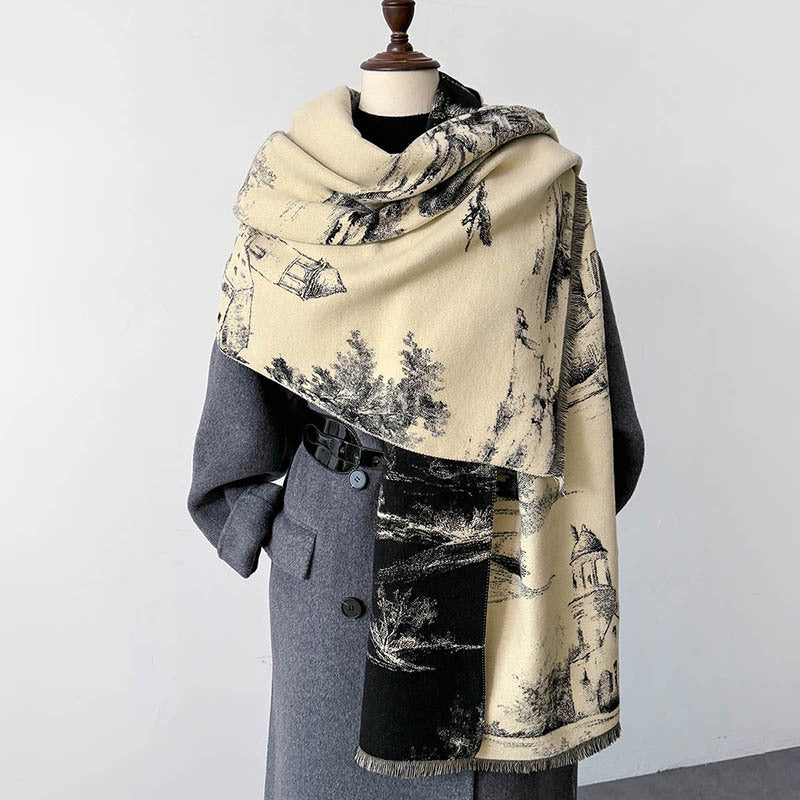 A large beige and black printed scarf with a scenic architectural pattern, draped over a gray coat on a mannequin torso against a plain light gray background.