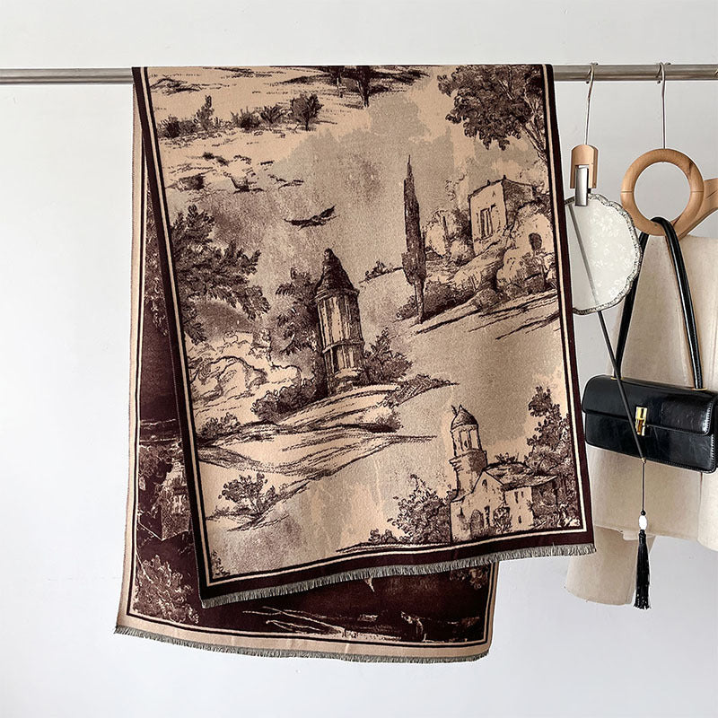 A beige and brown landscape tapestry scarf with a classic toile-style print of a Tuscan villa and trees, hanging from a metal rod next to a black handbag and a cream bag with a wooden ring handle.
