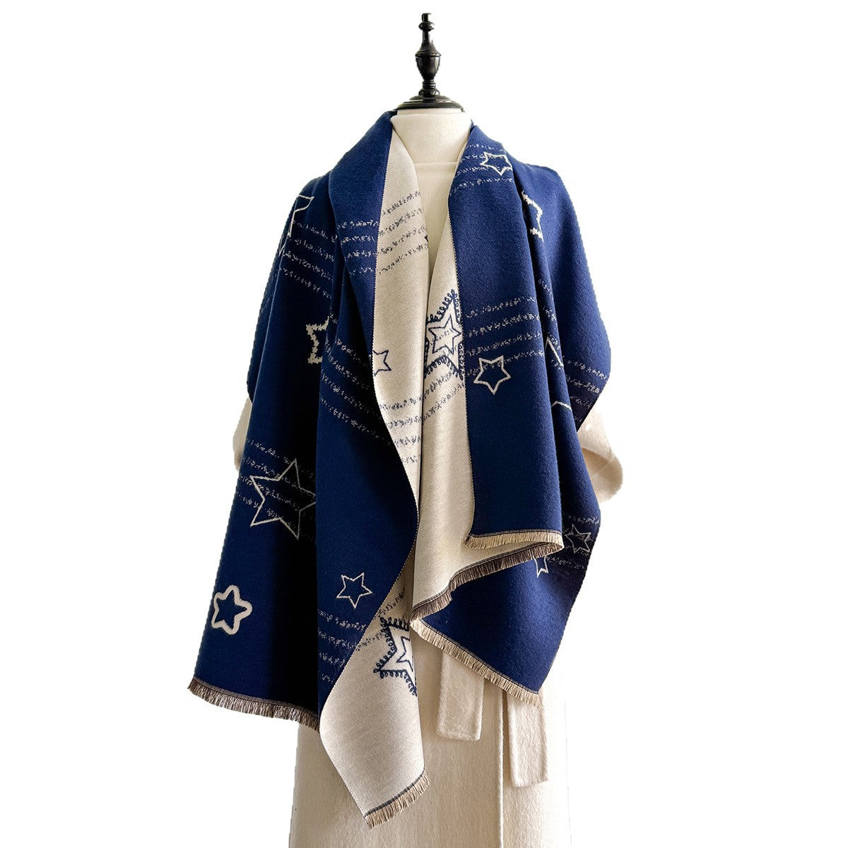 A navy blue and cream shawl with embroidered star patterns and script text, draped on a cream-colored mannequin torso against a white background.