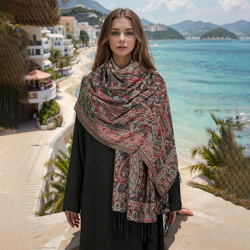 Woman wearing a patterned scarf with a scenic beach and mountains in the background