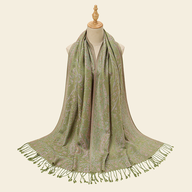 Green patterned scarf with tassels on a mannequin against a beige background