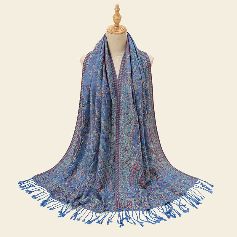 Blue patterned scarf with fringes on a mannequin against a beige background